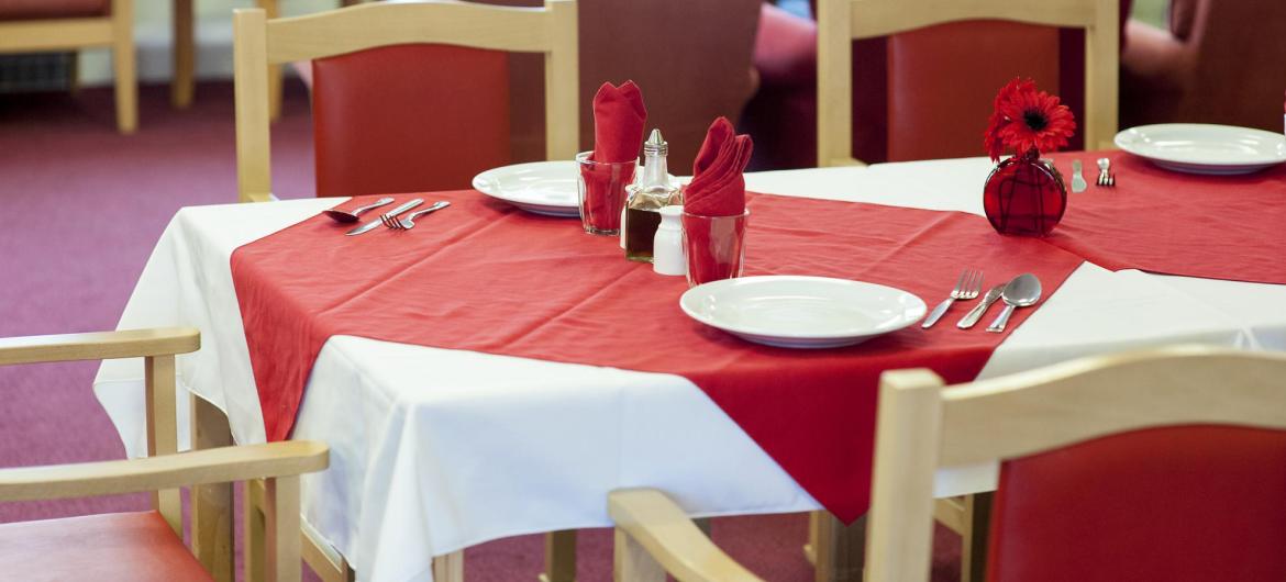 The dining room table at Time Court Residential and Nursing Home set with red and white coordinating tableware.