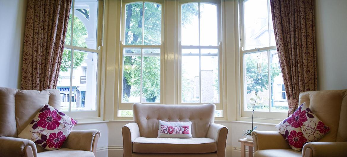 The lounge at The Winsor Nursing Home with comfortable seating and traditional bay windows.