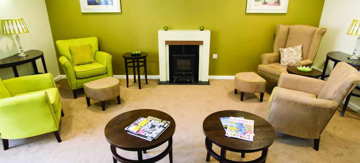 The lounge area in the Juniper House Residential Care Home with contemporary furnishings and an open fire.