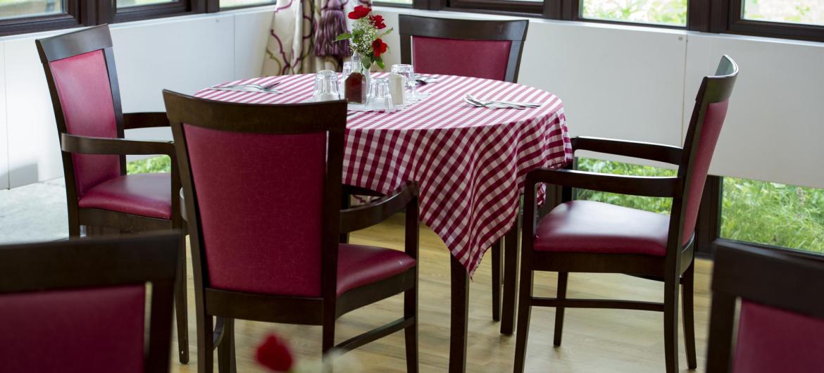 The dining room at Pinewood Residential Care Home with chequered table cloth and flowers.
