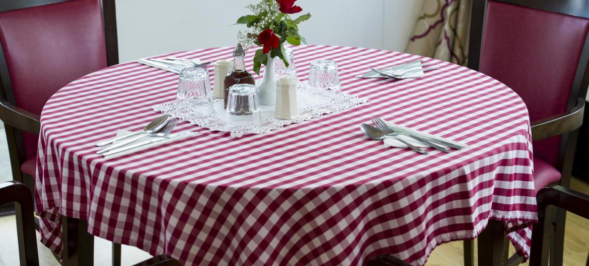 The dining room at Pinewood Residential Care Home with chequered table cloth and flowers.