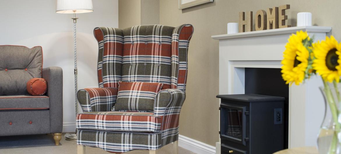 A cosy lounge with a log burning stove at Meadow View Residential Care Home.