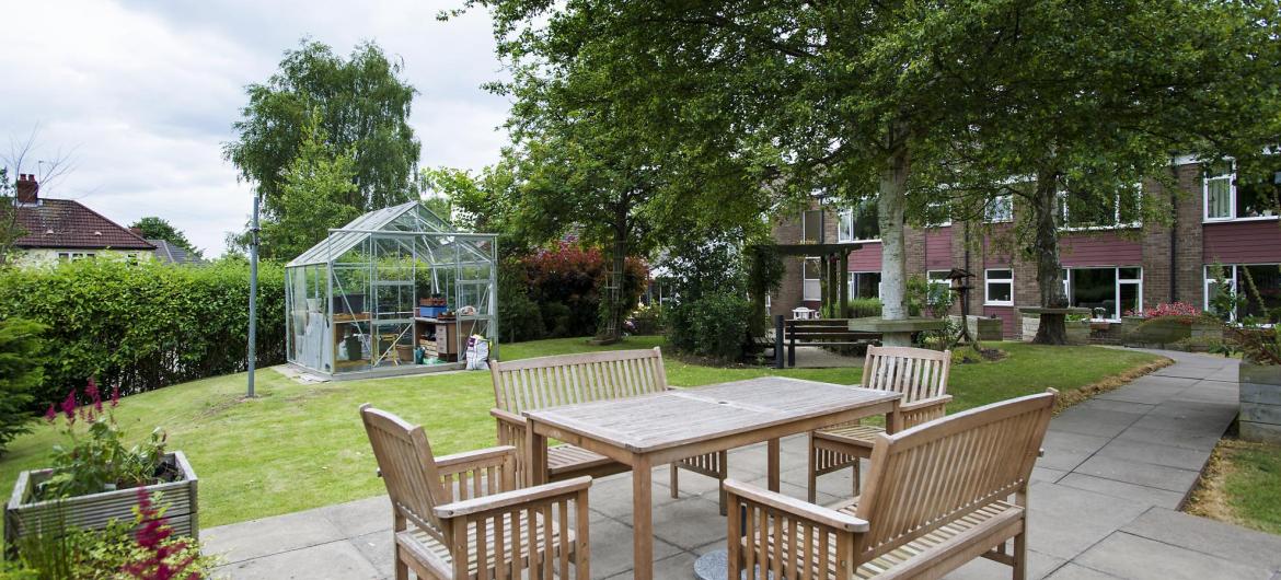 Wooden table and chairs in the courtyard garden at Bradwell Court Residential Care Home.