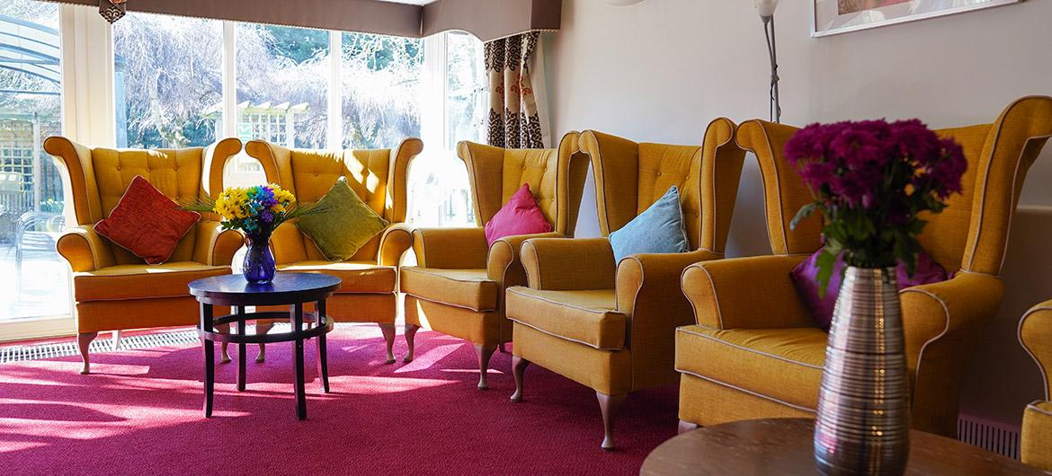 Interior lounge area of Asra House care home, featuring cozy blue seating.