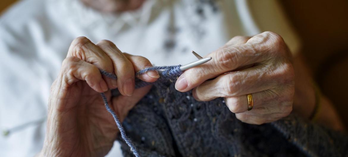 A resident sits knitting in the lounge.