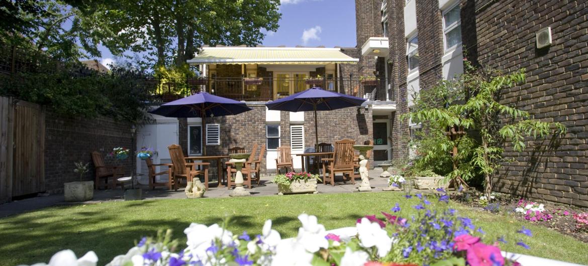 Tables, chairs and umbrellas in the pretty back garden at Forest Dene Residential Care Home.