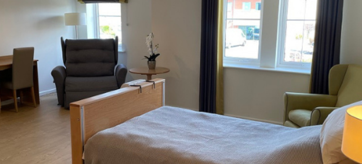A cosy bariatric bedroom furnished with a bed, chairs and a desk