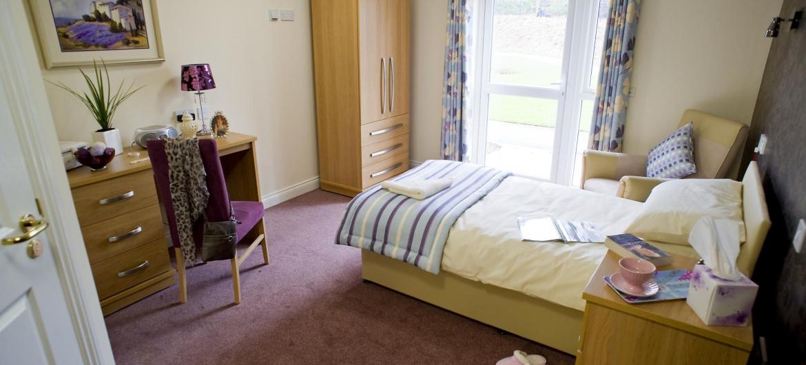 A stylish bedroom at Yarnton Residential and Nursing Home with coordinating wooden furniture.