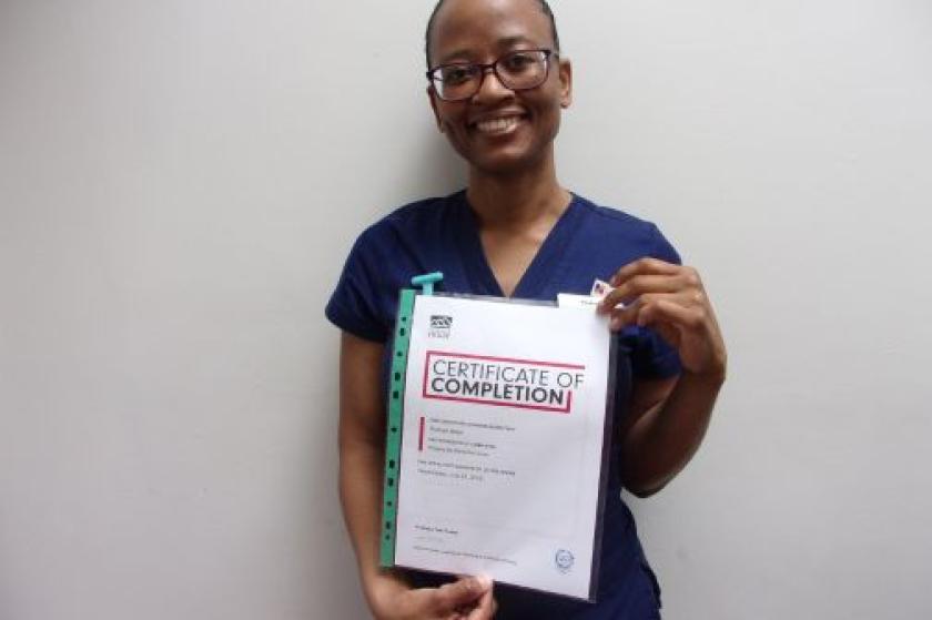 Roshell holding a certificate of completion and smiling