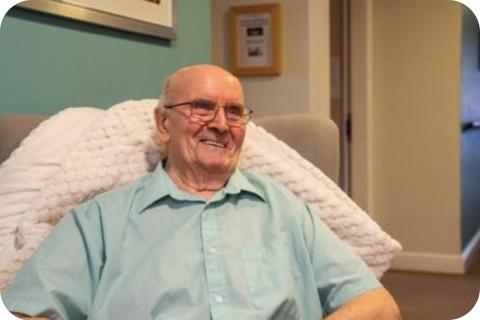 A male resident sat in an armchair smiling