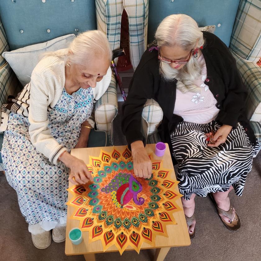 Two residents painting colourful decorations for Diwali