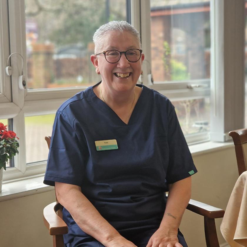 Sanctuary staff member Toni sat smiling in a chair at Lammas House Care Home