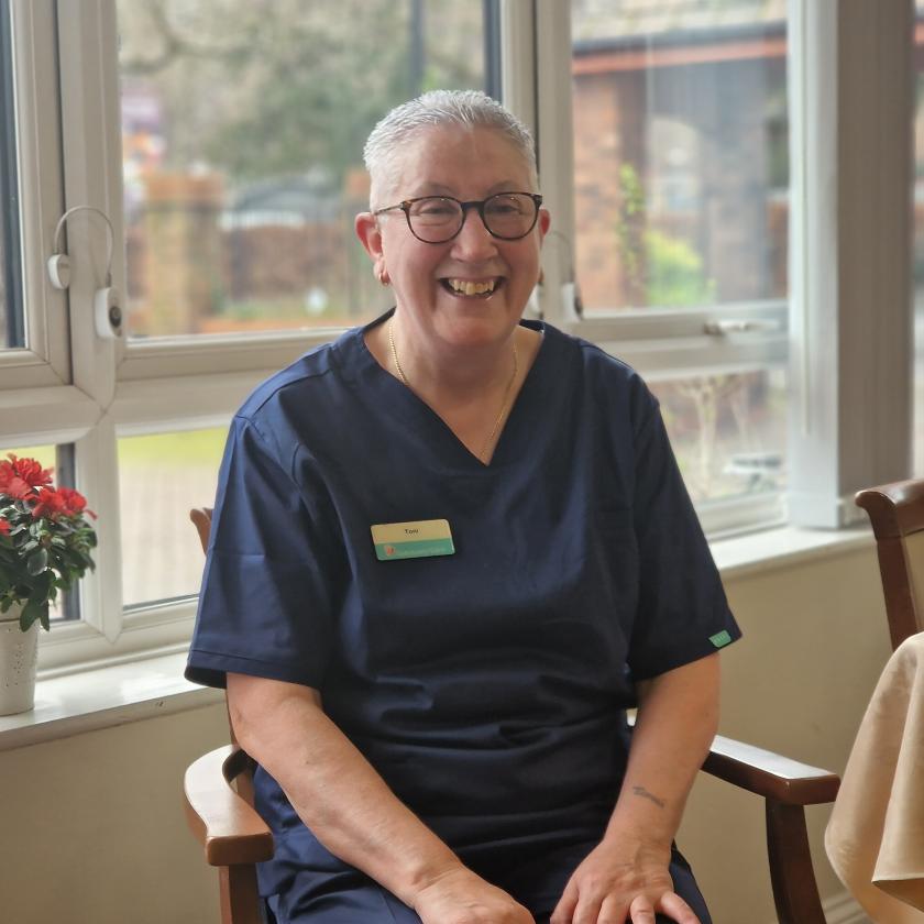 Staff member Toni Carrigan Staff member Toni Carrigan seated and smiling in front of a window
