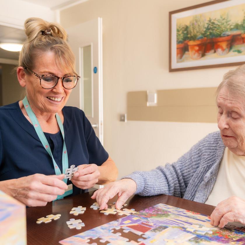 A care worker and resident sat together doing a puzzle