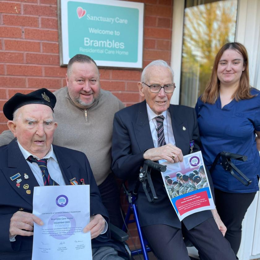 two veterans holding certificates with staff