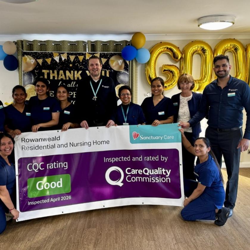 Group of staff celebrating a "Good" CQC rating with large gold balloons