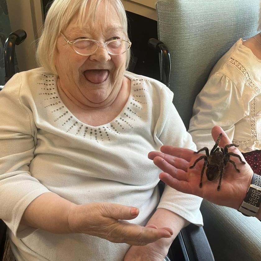Resident Eva Bate, smiling at someone holding a tarantula