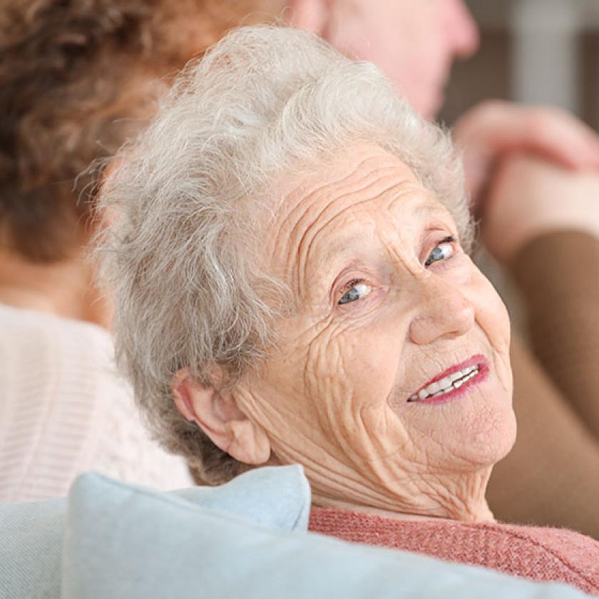 A happy care home resident smiles at the camera