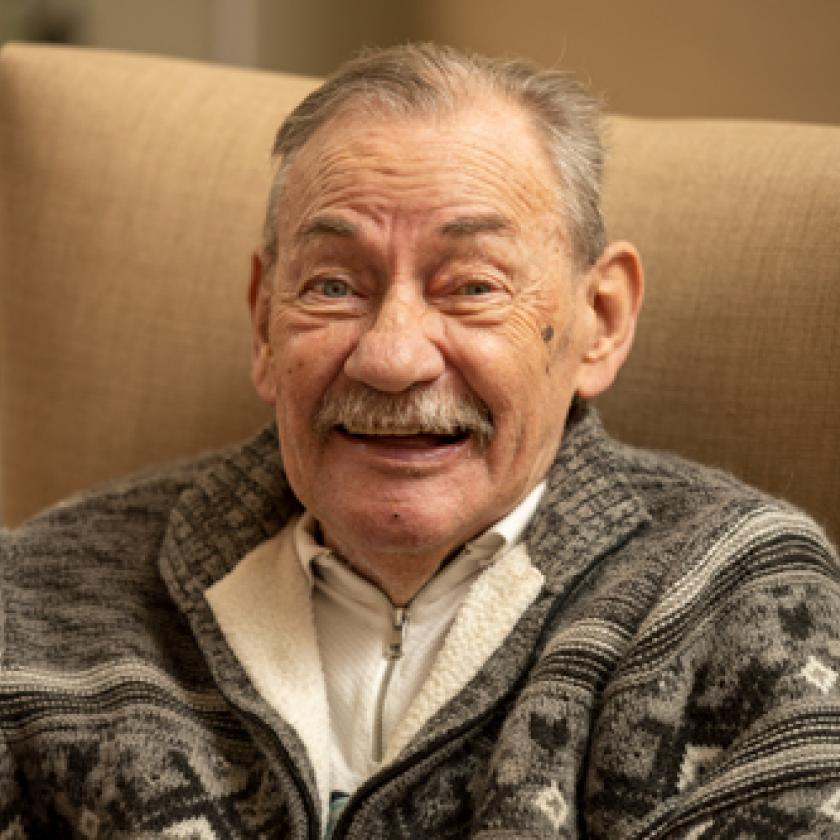 Male resident sitting in a chair with a large smile