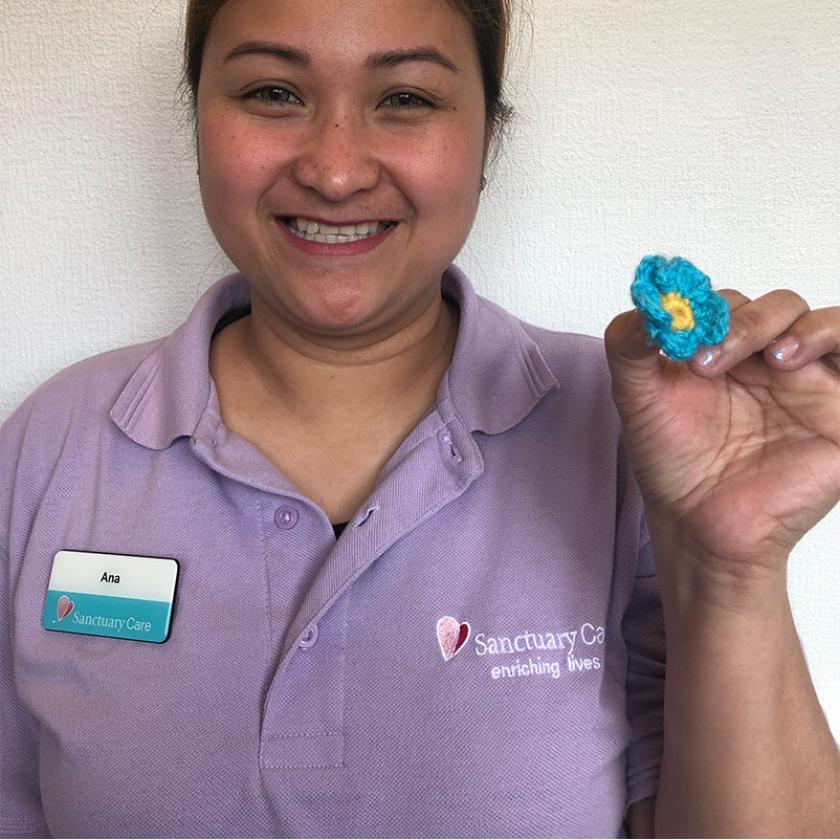 Female staff member at Beechwood holding a crochet floral badge