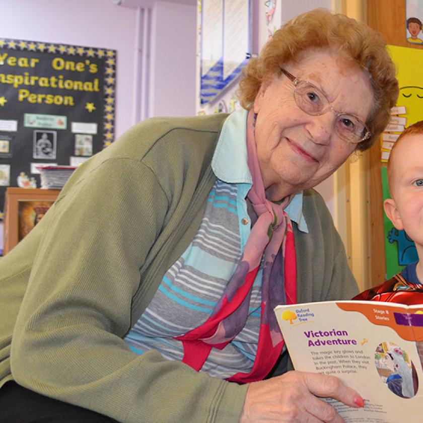 Care resident and a boy from a local school reading together