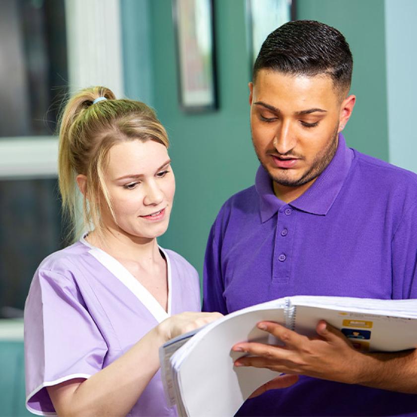 Sanctuary Care staff looking at a book